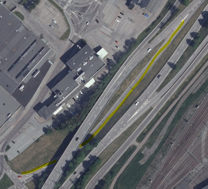 Flygbild över komplicerat vägkors med markerade körfält i gult; visar avfart till vänster vid Lundbyleden nära industriområde.