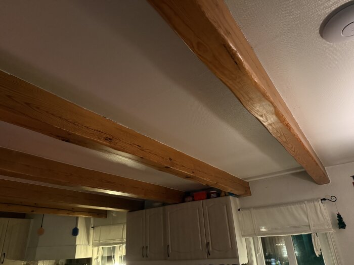 Tak med synliga träbjälkar över köksskåp i ett kök med låg takhöjd, del av renoveringsfunderingar.