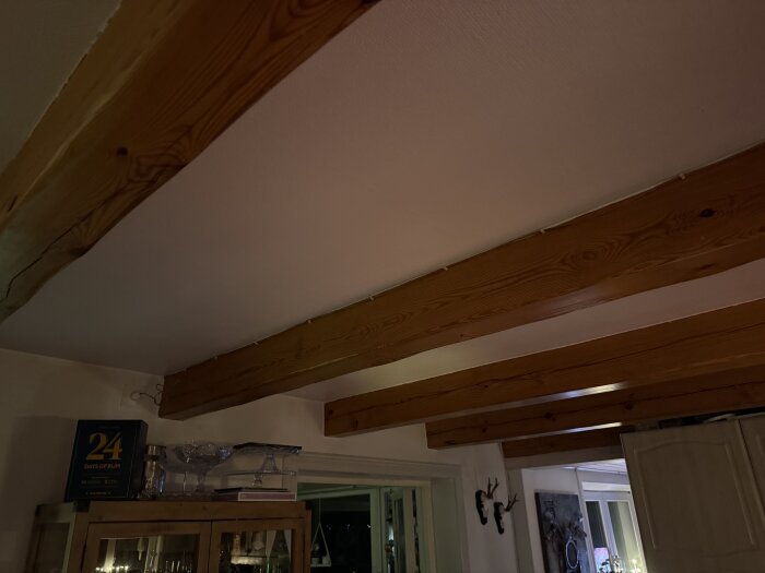 Tak med synliga träbjälkar i ett kök med lågt i tak, inklusive detaljer som skåp och fönster.