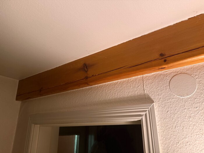 Trätakbjälke synlig i köket ovanför en dörr, del av ett gammalt hus, påverkar planering för köksrenovering.