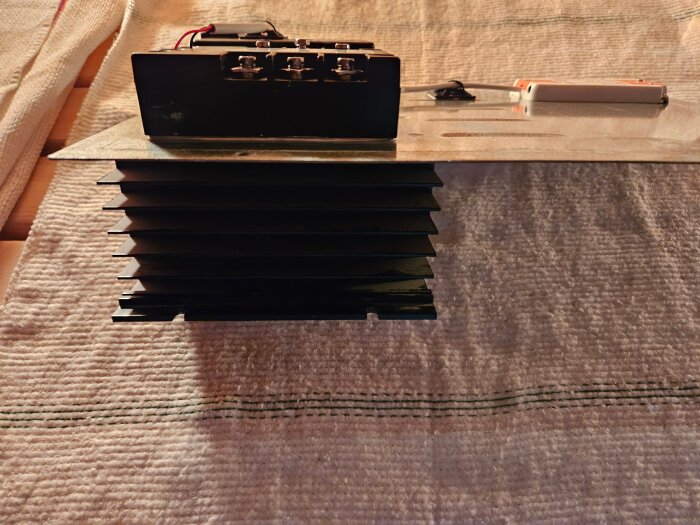 Svart kylfläns och elektroniska komponenter på metallplatta, del av bastuaggregatmodifikation med Arduino och SSR.