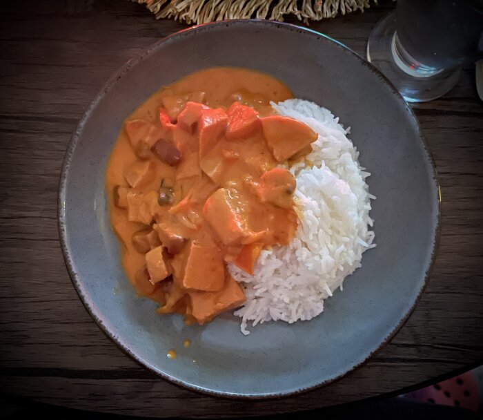 Korvgryta med korv, salami och squash i tomatsås, serverad med ris på en tallrik.