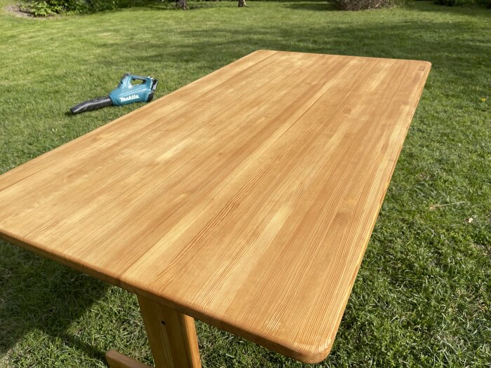 Nyoljad träbordsskiva i trädgård, gräsmatta i bakgrunden.