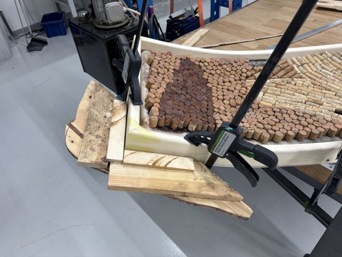 Träram med korkar fastklämd under arbete i verkstad.