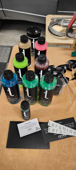 Flaskor med rengöringsprodukter från ter shine, i olika färger och storlekar, på ett bord tillsammans med sprutmunstycken och informationskort.