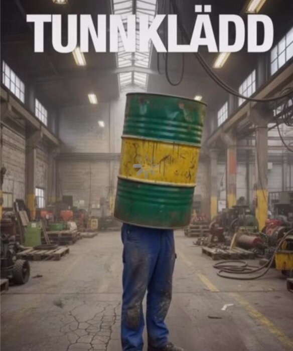 Person i blå byxor bär en stor grön och gul tunna i en fabrik med texten "TUNNKLÄDD" ovanför.