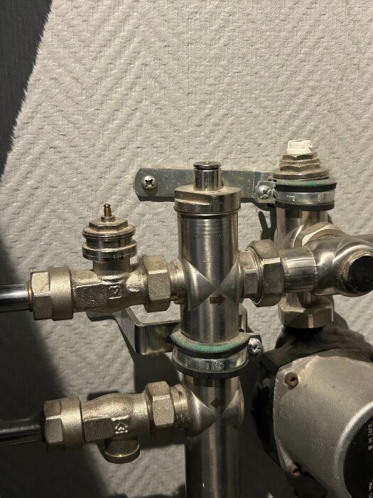 VVS-ventilsystem med flera kopplingar i metall, del av golvvärmeinstallation; synlig gänga och saknad termostatindikator.