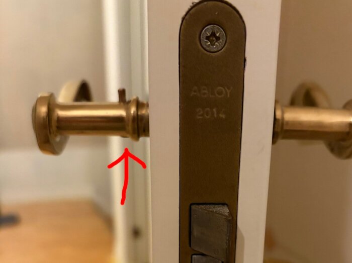 Röd pil pekar mot en del av ett dörrlås av märket Abloy.