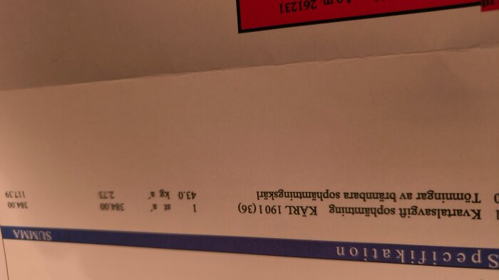 Upp och nervänd bild av ett dokument med text om moms 25% och summan 384.00.