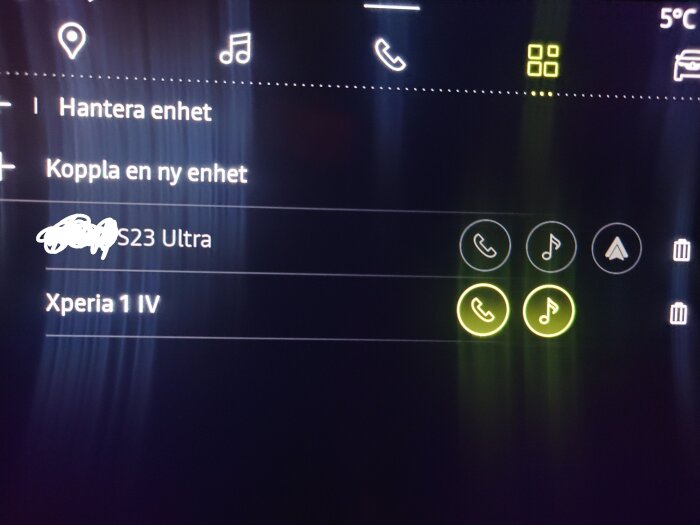 Bild på en bils infotainmentsystem som visar anslutna enheter: "S23 Ultra" och "Xperia 1 IV" med ikoner för telefon och musik. Temperatursiffra och ikoner högst upp.