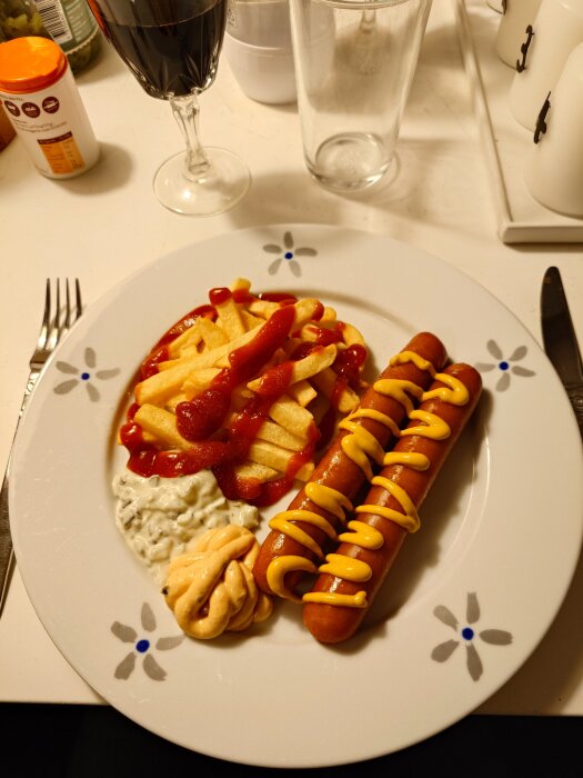 Tallrik med pommes frites och två korvar toppade med ketchup och senap, samt tre olika såser bredvid.