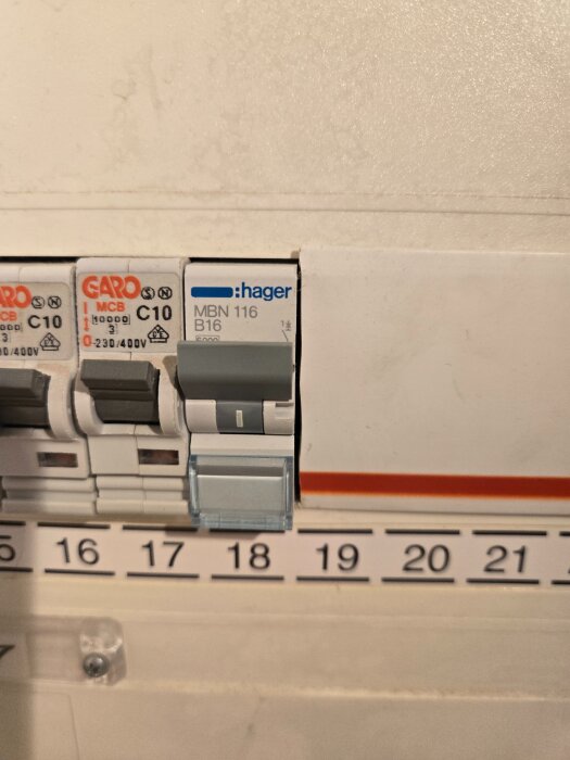 Elektrisk säkringsskåp med flera automatsäkringar, inklusive märken från Garo och Hager, och numrerade platser för säkringar.