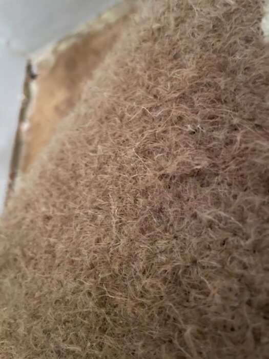 Närbild av brun plastmatta från 70-talet, med fokus på fiberskiktet som kan innehålla asbest.