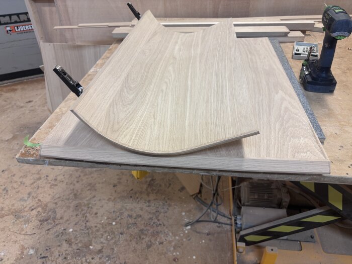 Slipade träskivor för en bar på ett arbetsbord, redo för ytbehandling, med en borrmaskin synlig i bakgrunden.