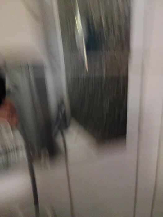 Oskarp bild av ett badrum med duschvägg och suddiga konturer.