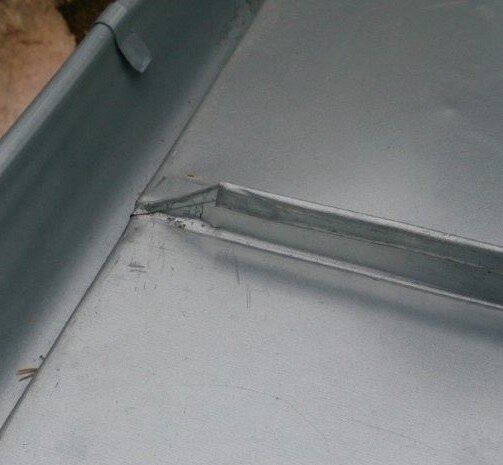 Plåtbeslag med bockad kant och synliga fogar på en byggnad.