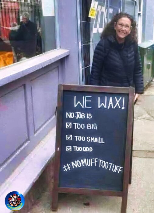 En kvinna ler bredvid en skylt utanför en byggnad. Skylten säger "WE WAX! No job is too big, too small, too odd" och visar hashtaggen #NOMUFFTOOTUFF.