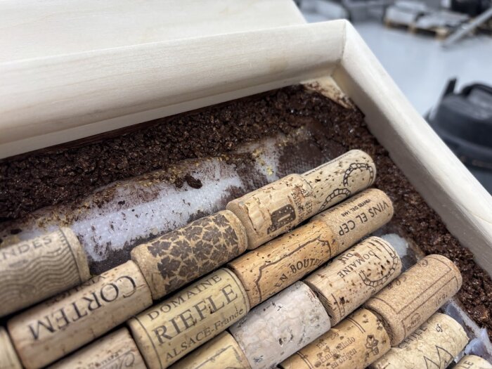 Rader av vinkorkar monterade i en träram med mörk fyllning av mald kork och silikon inuti.