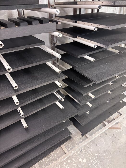 Svarta hyllplan på torkställning i verkstadsmiljö.