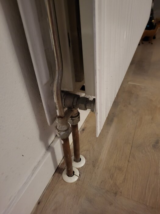 Radiator med röranslutningar och en läckande ventil. Synliga rör kopplar radiatorn till golvet. Inlägget nämner problem med avstängning.