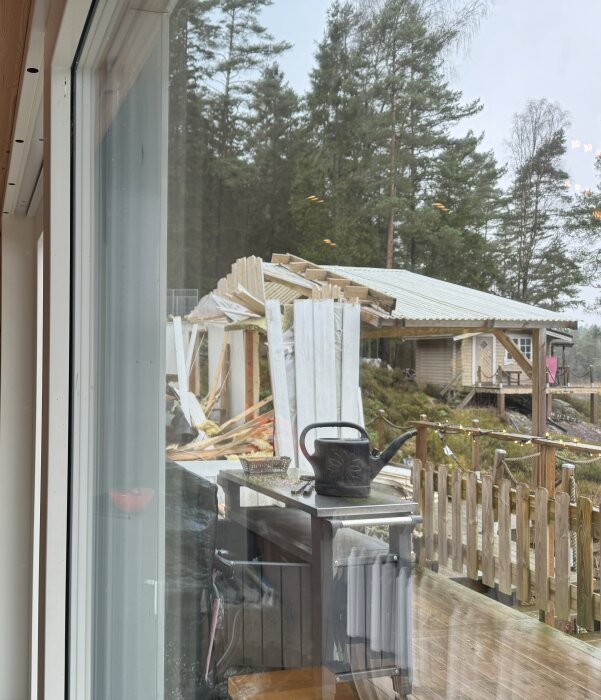 Rivningsarbete av en stuga i skogslandskap med byggmaterial och verktyg på en altan.