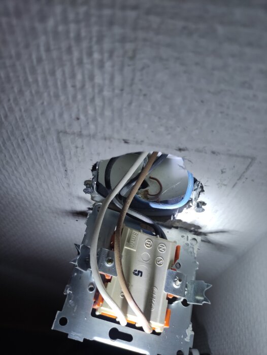 Eluttag med synliga kablar, inklusive ledare och nolla, monterat i en vägg utan jordat våguttag.