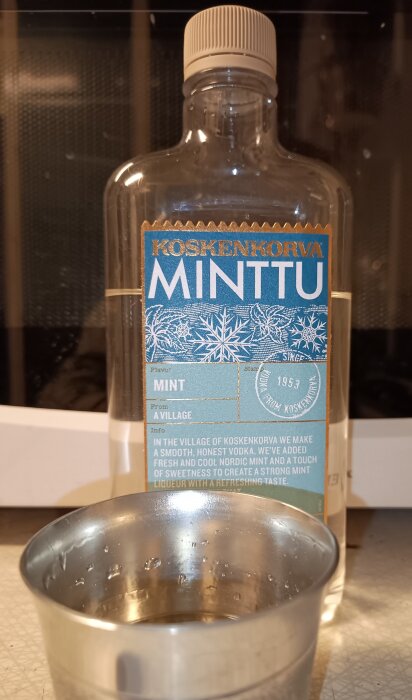 Flaska Koskenkorva Minttu och en metallkopp med dryck.