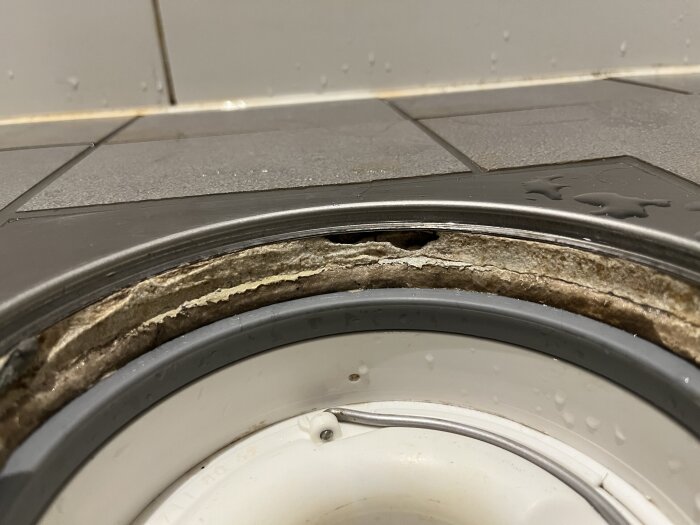 Golvbrunn i dusch med saknad fog och synlig slitage på kanterna, orolighet om vattentäthet nämns.