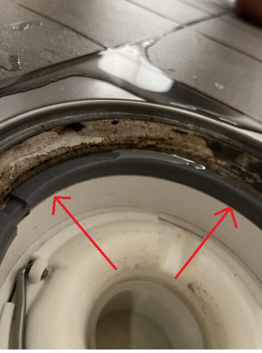 Tätning vid avloppsbrunn med fokus på fästmassan. Röd pil markerar området mellan brunnen och klämringen, visar potentiell risk.