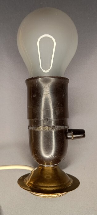 Äldre fotogenlampa elektrifierad med lamphållare och glödlampa.