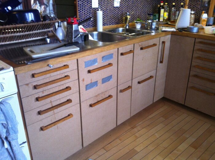 Hemmagjorda köksluckor i trä med handtag, del av ett handbyggt kök med stommar och lådor, före lackering.