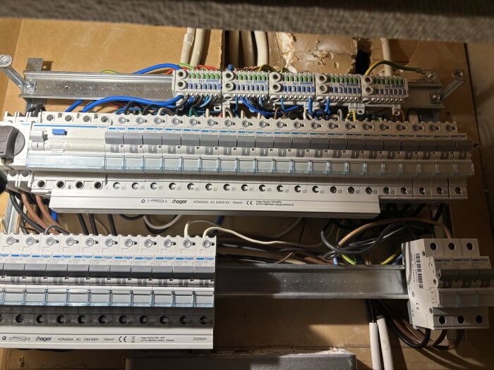 Bild på en elcentral med flera säkringar och kablar, vissa av dem oregelbundna i färg och skalning; ifrågasatt utförande under köksrenovering.