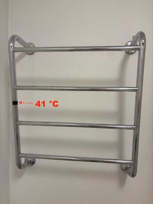 Kromad handdukstork i badrum med mätt temperatur på 41 °C, monterad på vit vägg.