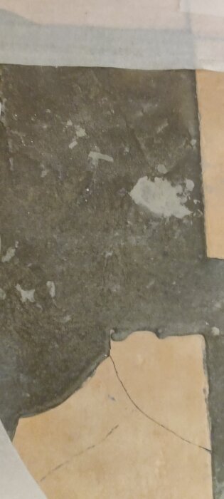 Skadad klinker med fyllning av flytspackel på trägolv, synlig spricka och slitage i materialet.