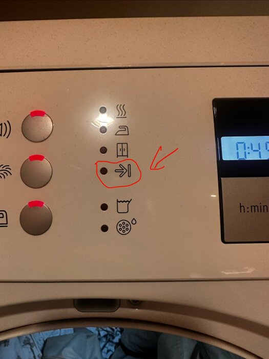 Tvättmaskin med kontrollpanel och symboler, inklusive en rödmarkerad pil som pekar nedåt, samt digital display som visar 0:41.