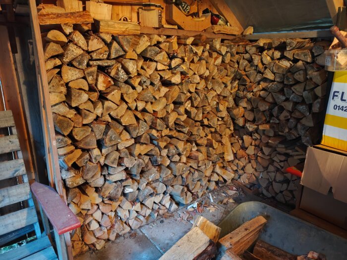 Vedbod fylld med staplad ved, uppskattat till 2m³.