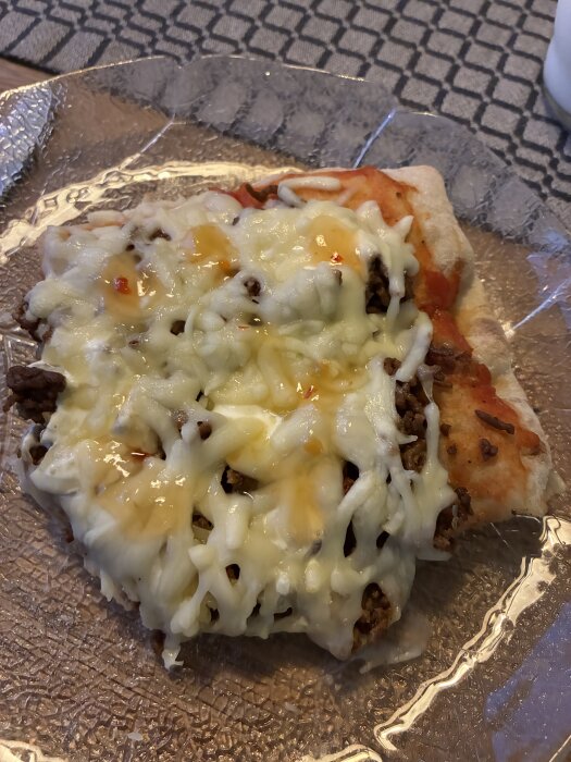 Tacorester serverade på ett fluffigt Pinsabröd med smält ost och köttfärs, fotat halvvägs in i måltiden på en genomskinlig tallrik.