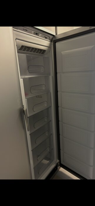 Öppen frys med flera lådor, visar tätningslisten och inredningen. Frågeställning om frysens funktion.