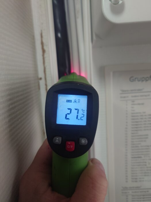 Infraröd termometer visar 27,2°C nära en kabel, med röd laserpunkt.