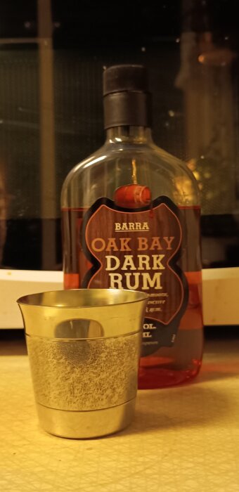 Flaska med Oak Bay Dark Rum och en metallkopp framför, relaterad till finska självständighetsdagen.