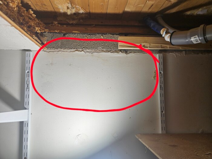 Blöt källarvägg med vattenfläck, omkring 30 cm under marknivå. Röd cirkel markerar det fuktiga området, omgivet av torra delar av väggen.