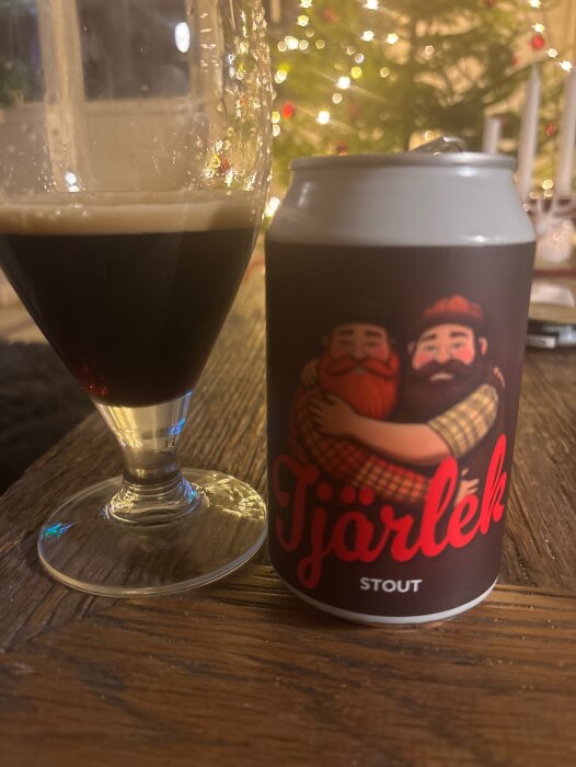 Öl i glas och burk med etikett "Tjärlek Stout", julgran i bakgrunden.