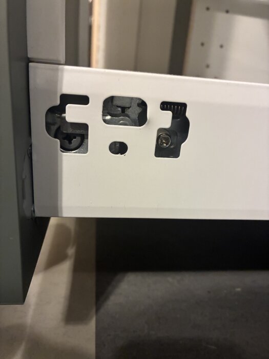 Utdragsskåpets mekanism och fästen syns på närbild, del av möbelmontering utan synliga instruktioner.
