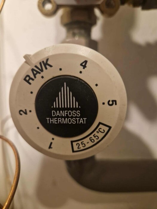 Termostat med Danfoss-märke och temperaturintervall 25-65°C, inställd på position 4.