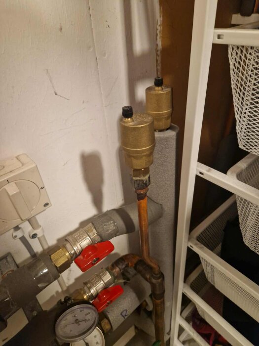 Två "tacovent" automat-luftare installerade på ett shuntsystem, med rör, ventiler och en tryckmätare synliga i bakgrunden.