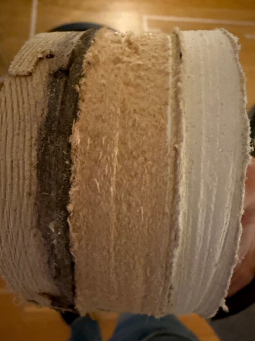 Närbild av ett tvärsnitt av väggmaterial, inklusive trä, isolering och gips, i ett radhus från 60-talet, för ett badrumsprojekt.