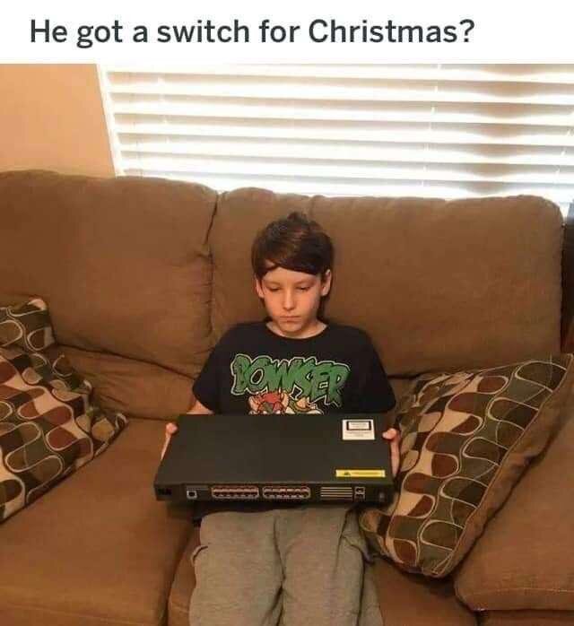 Pojke sitter på soffa och håller i en nätverksswitch, med texten "He got a switch for Christmas?" ovanför.