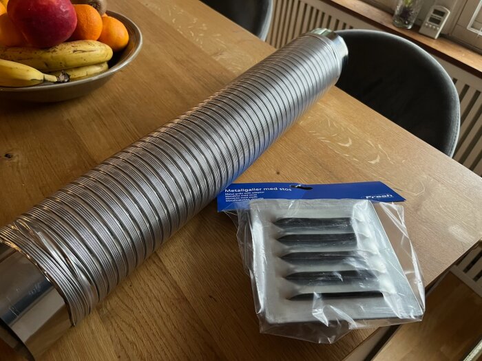 Flexslang och ventilationsgaller på ett bord, bredvid en fruktskål.