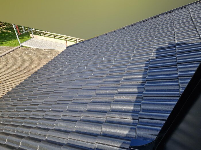 Nyinstallerat tak med glänsande svarta takpannor i solljus, granskat för korrekthet.