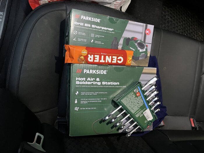 Verktyg och choklad i bilsäte: borrslipmaskin, lödstation och chokladkaka av märket Center.